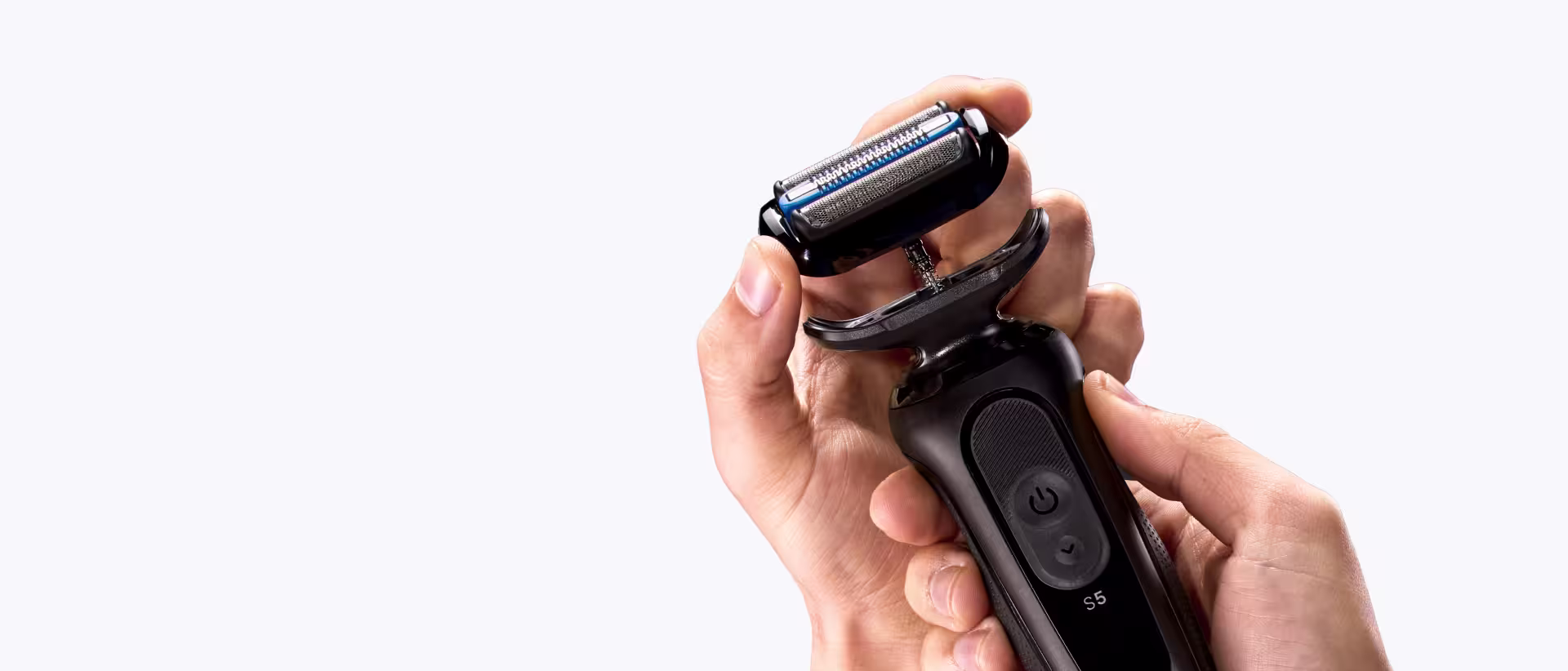 Hands holding a black electric shaver with its shaving head detached. Hands holding a black electric shaver with its shaving head detached.
