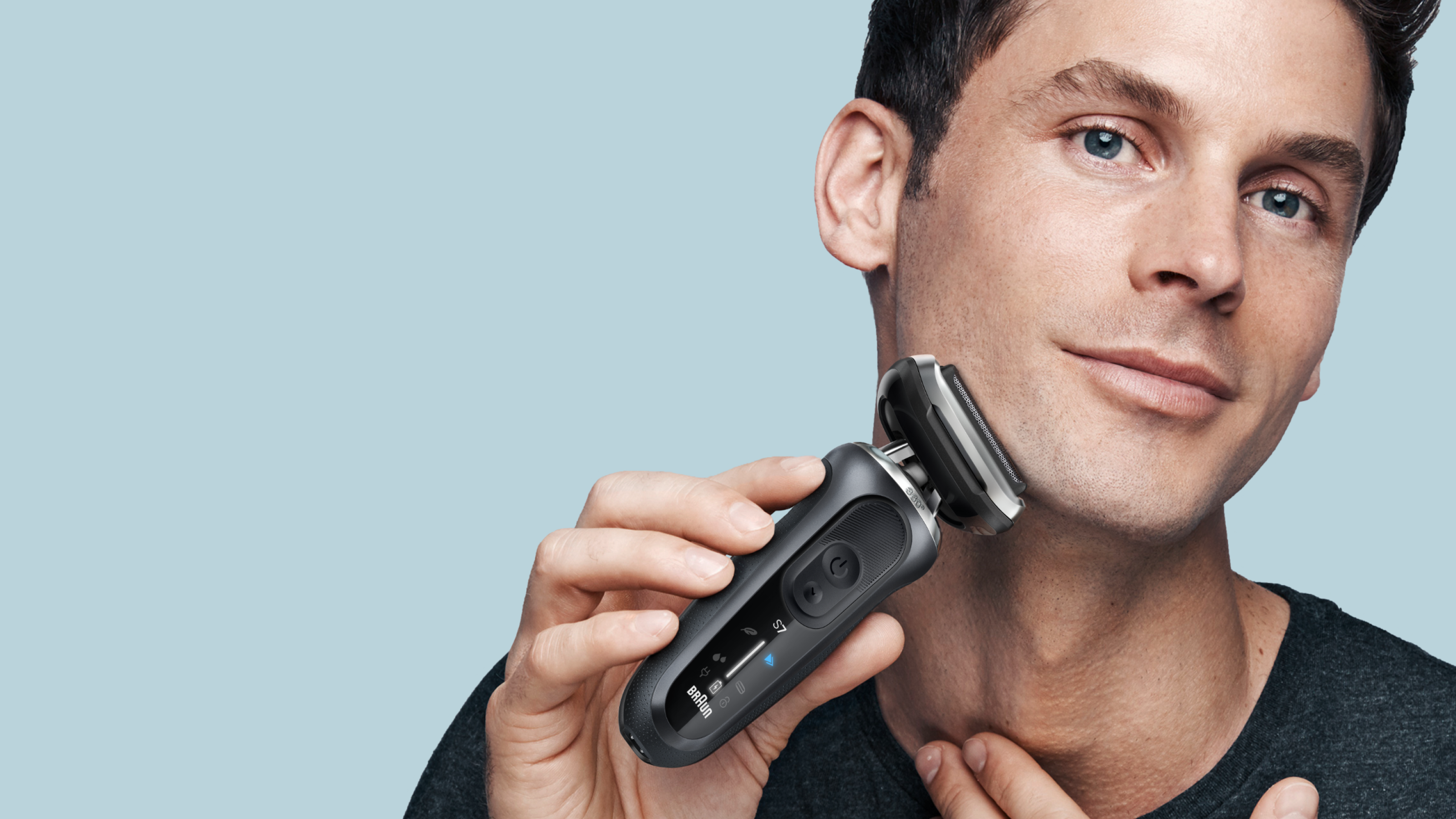 Man shaving his face with Series 7 device, holding the device in one hand, placing his other hand on his neck for support