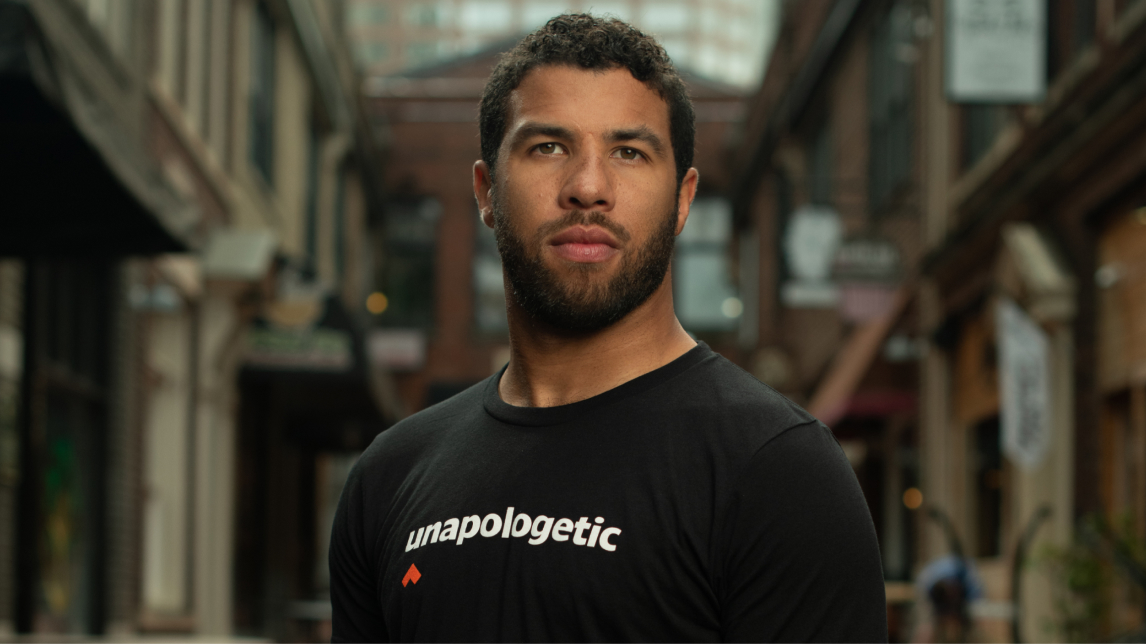 Bubba Wallace wearing an unapologetic sweatshirt while staring into the distance. 