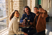 A group of friends enjoying a creamy pint while taking a selfie.