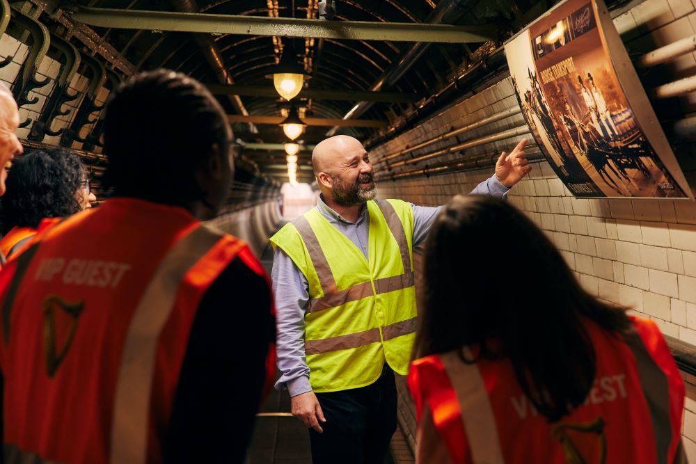 Tour guide pointing to a picture in the wall while visitors listen to him