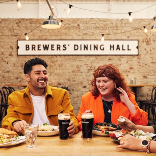 Large image of a group of friends laughing and enjoying their meal at the Brewers’ Dining Hall, with more pairings of mussels and Guinness Draught.