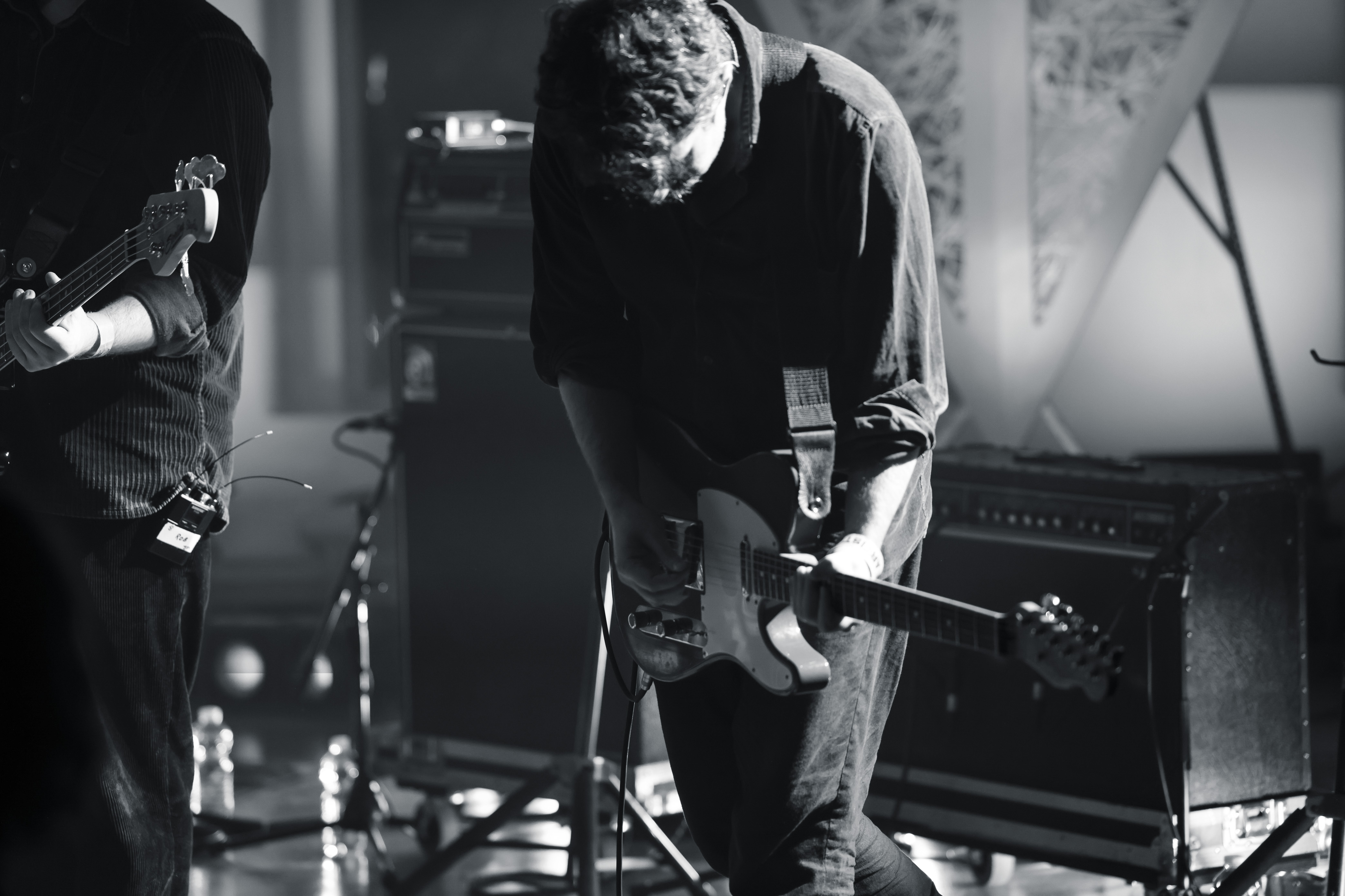 A black and white image of the artist playing a guitar on the stage