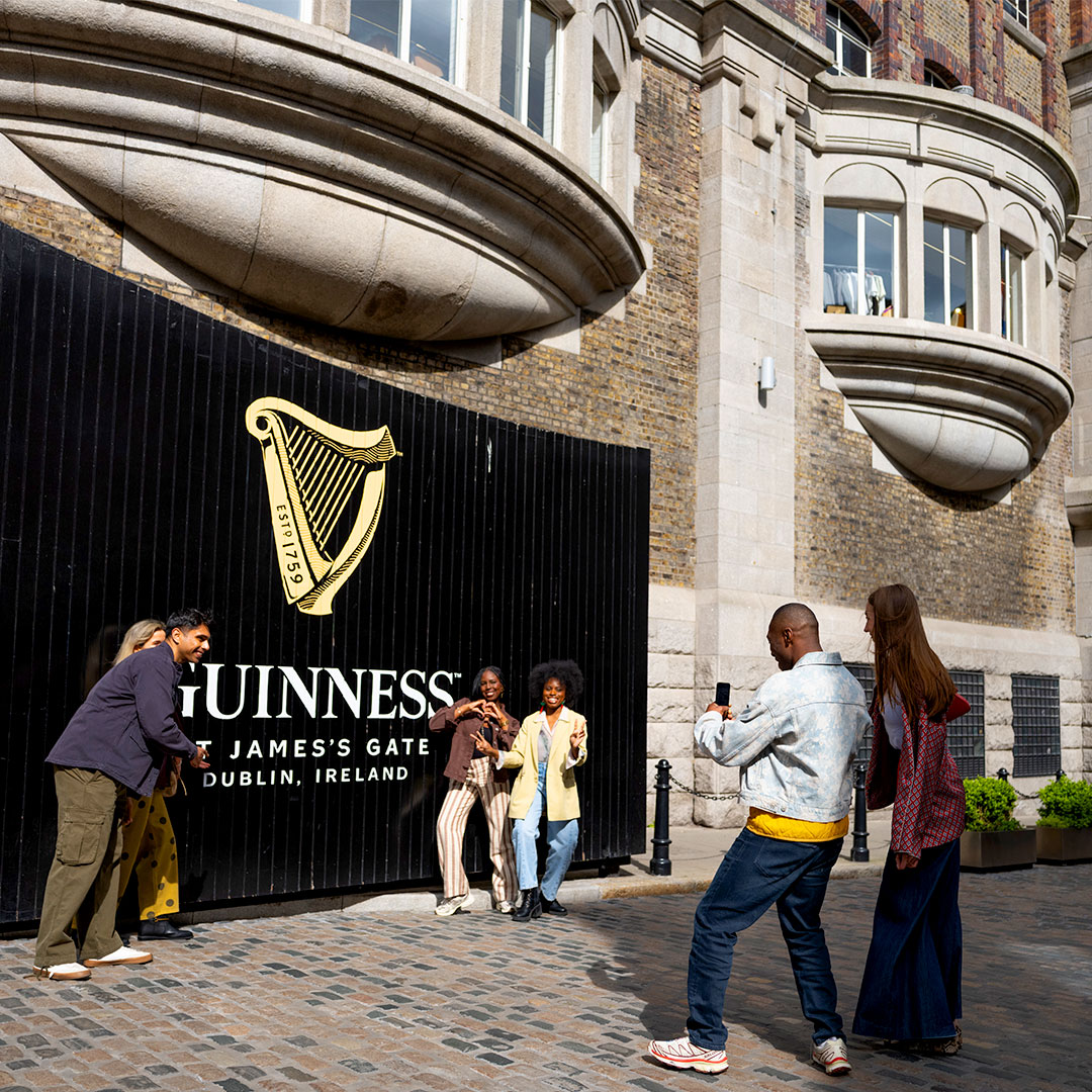 A group of friends clicking pictures in front of the black gates with the mobile phone