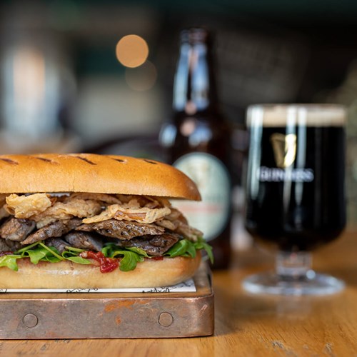 Arthur’s Bar steak sandwich made from prime Irish striploin, served on a brioche sub roll, with spicy Ballymaloe relish and crispy onions.
