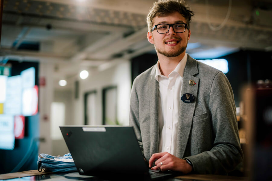 A Guinness Storehouse employee wearing a suit and working on his laptop.