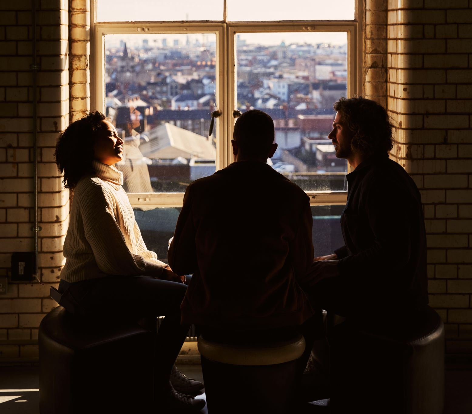 Three friends seated at a table beside the window, laughing and enjoying the view