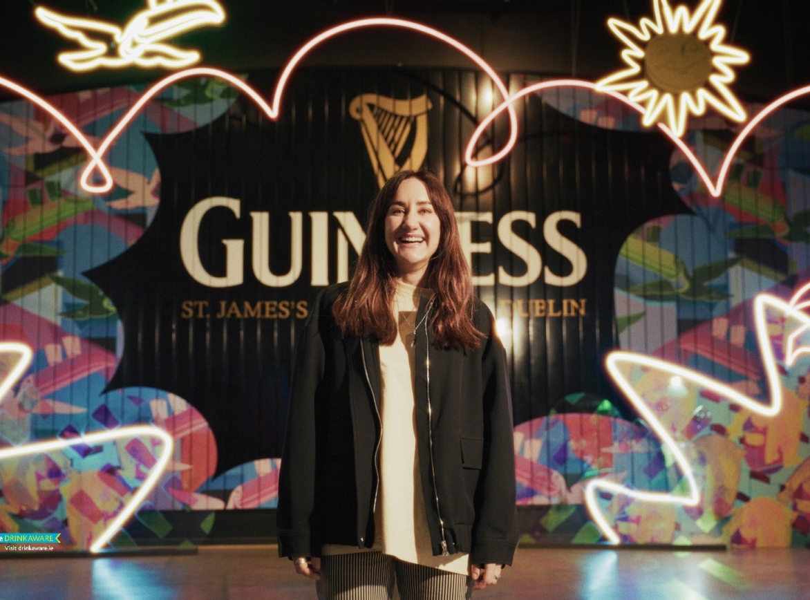Leah Hewson standing in front of Guinness gate decorated with neon summer elements
