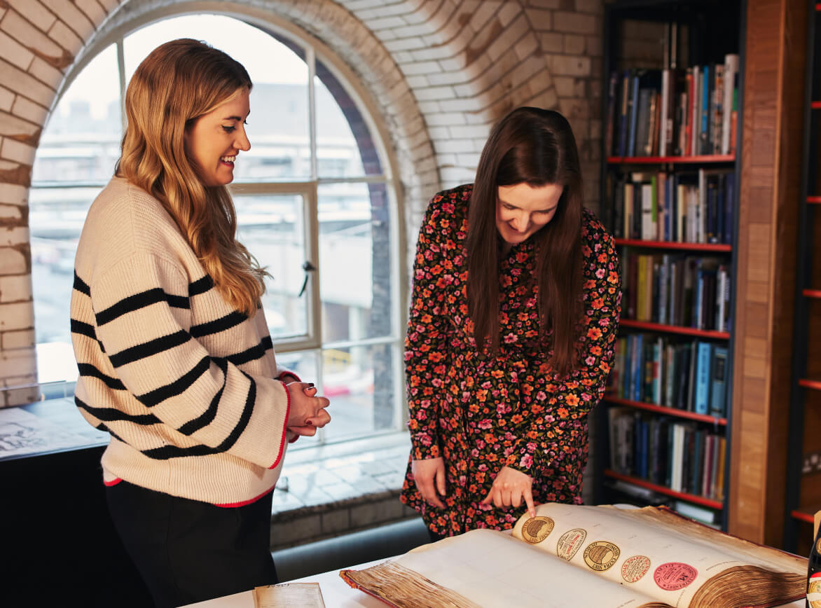 Archive session in the research room, two women with label ledger and Gilroy painting.