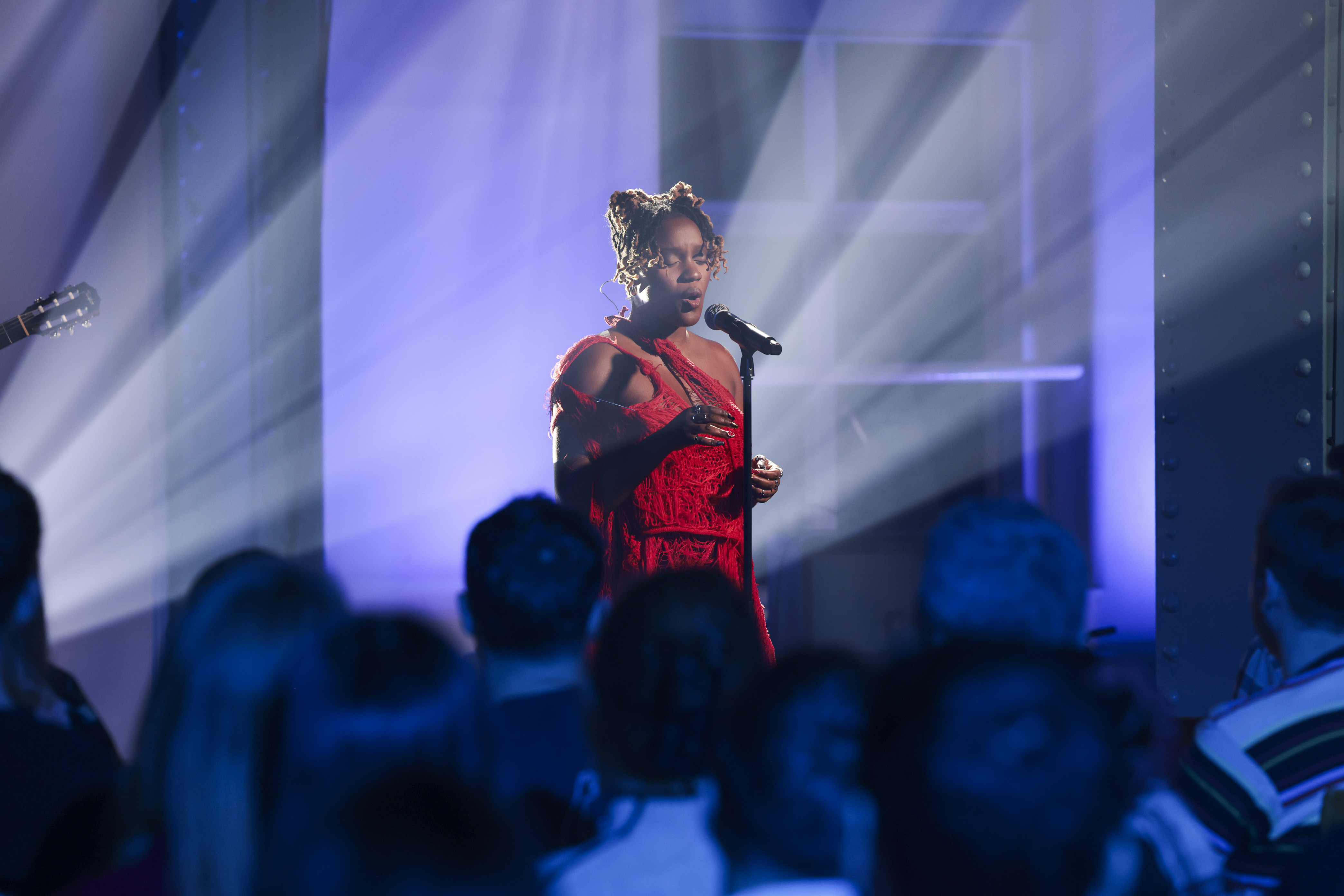 A female singer wearing a red dress performing in front of the audience