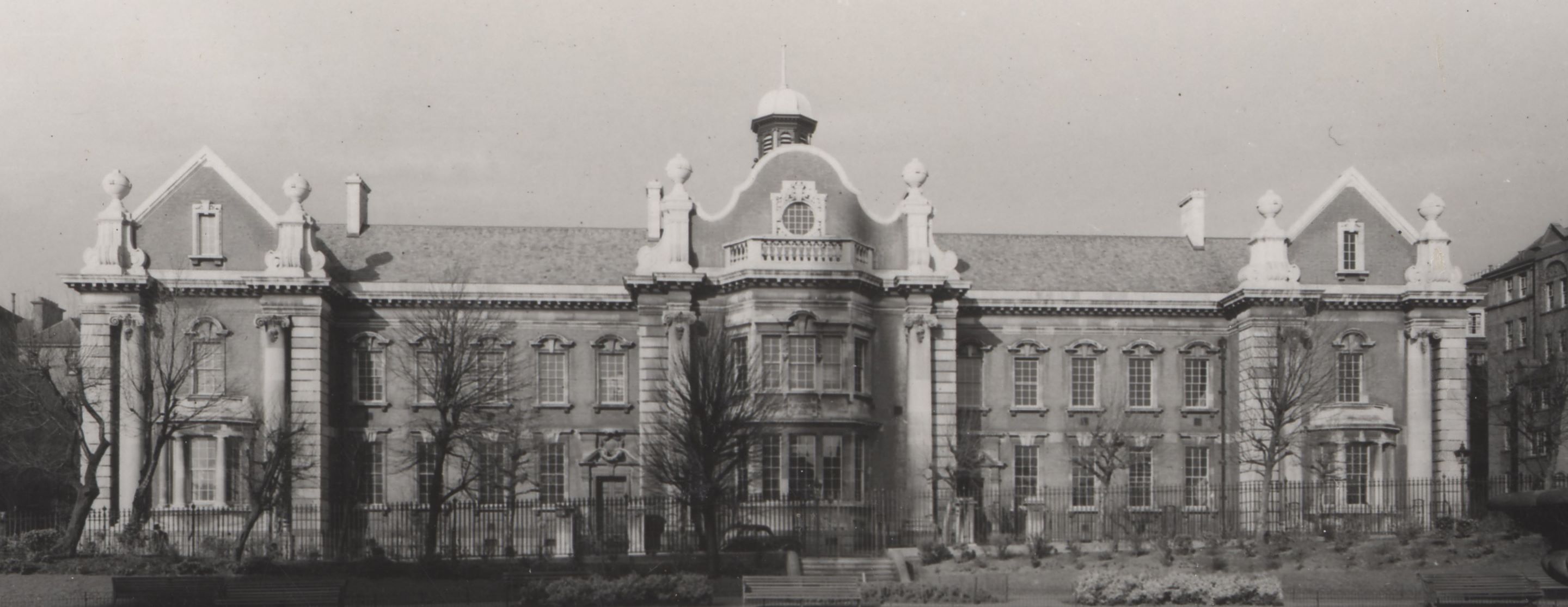 An old photograph of a large building with fountain in the foreground.