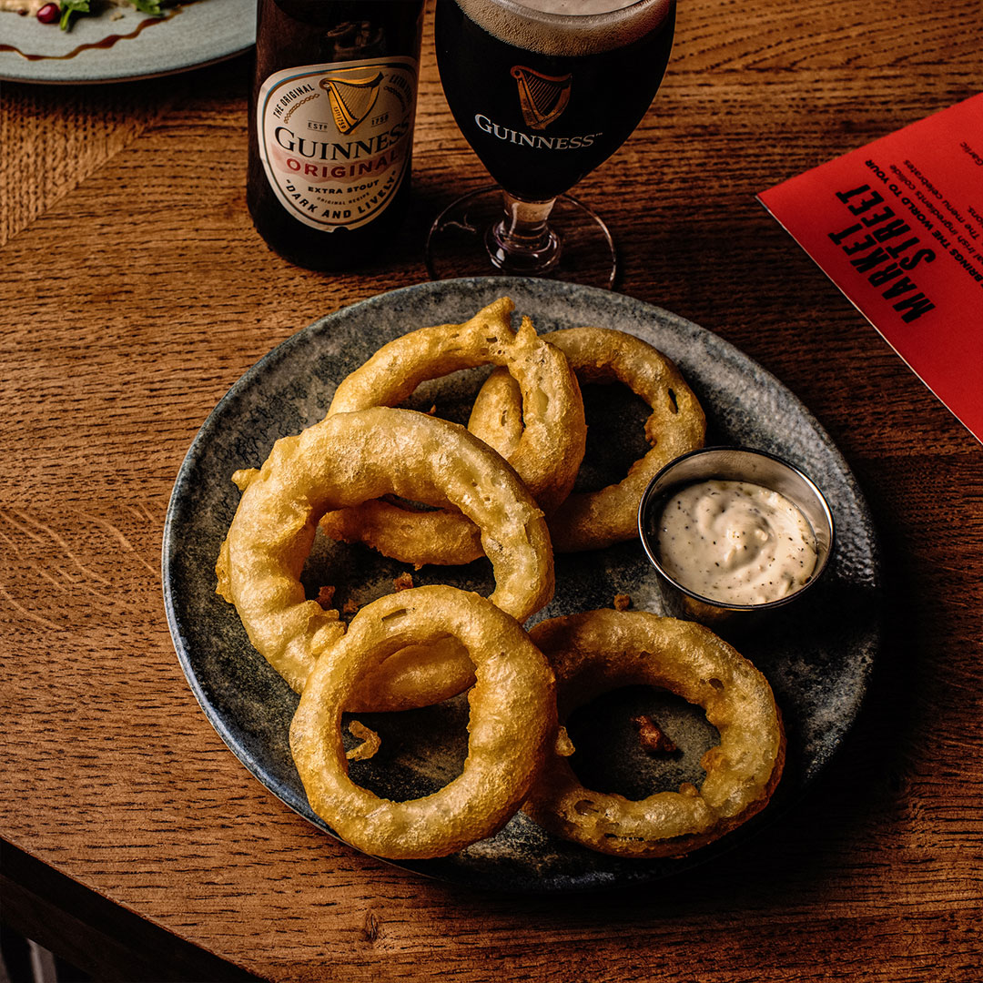 Battered onion rings served with dipping sauce and Guinness