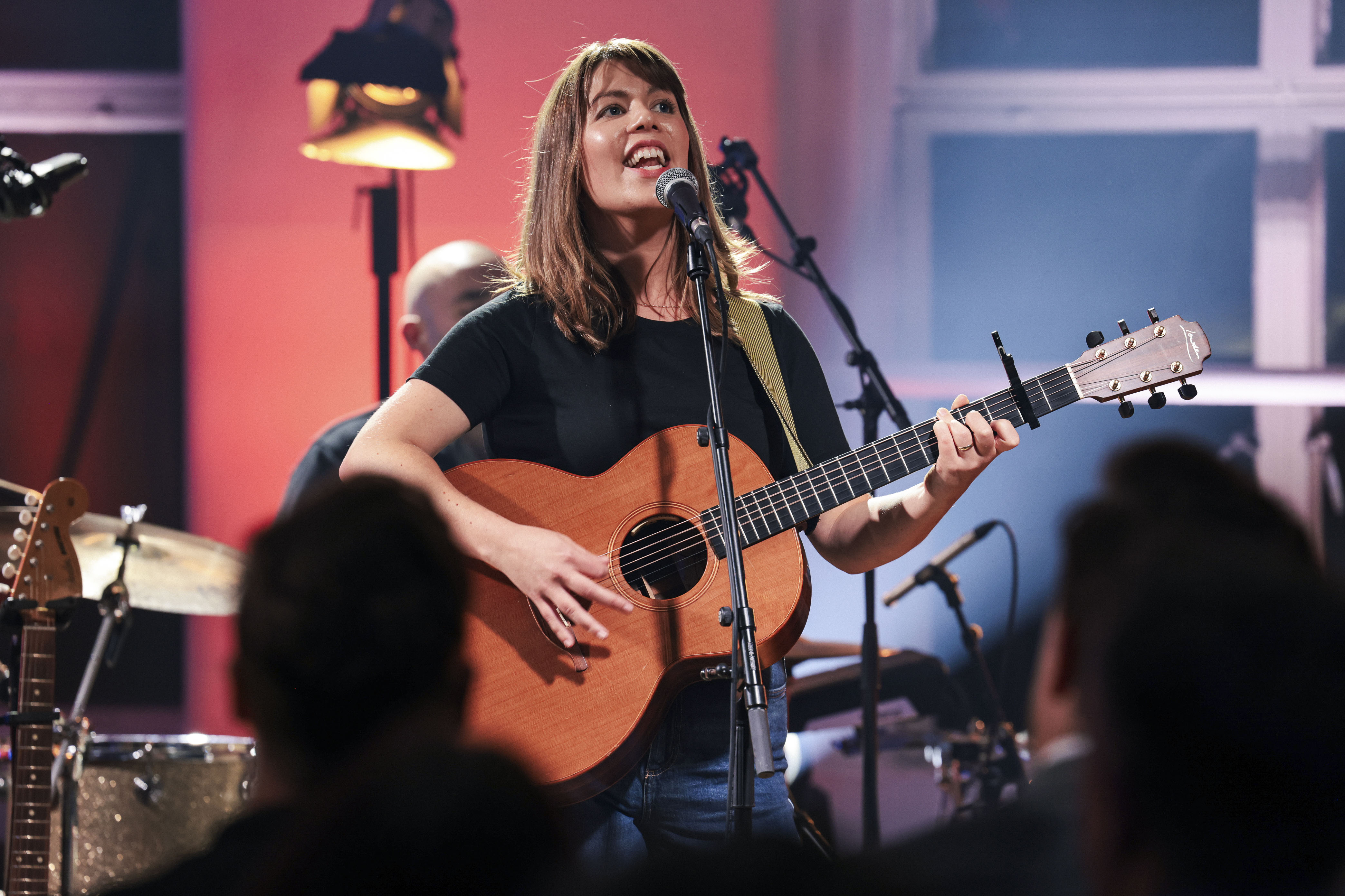 A female artist signing and playing a guitar at Other Voices