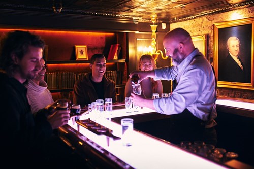Tour guide pouring the Guinness extra stout in the visitor's glass while explaining the differences on the types of Guinness