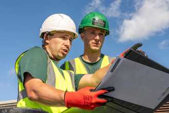 Roofing apprentice learning from supervisor on the roof