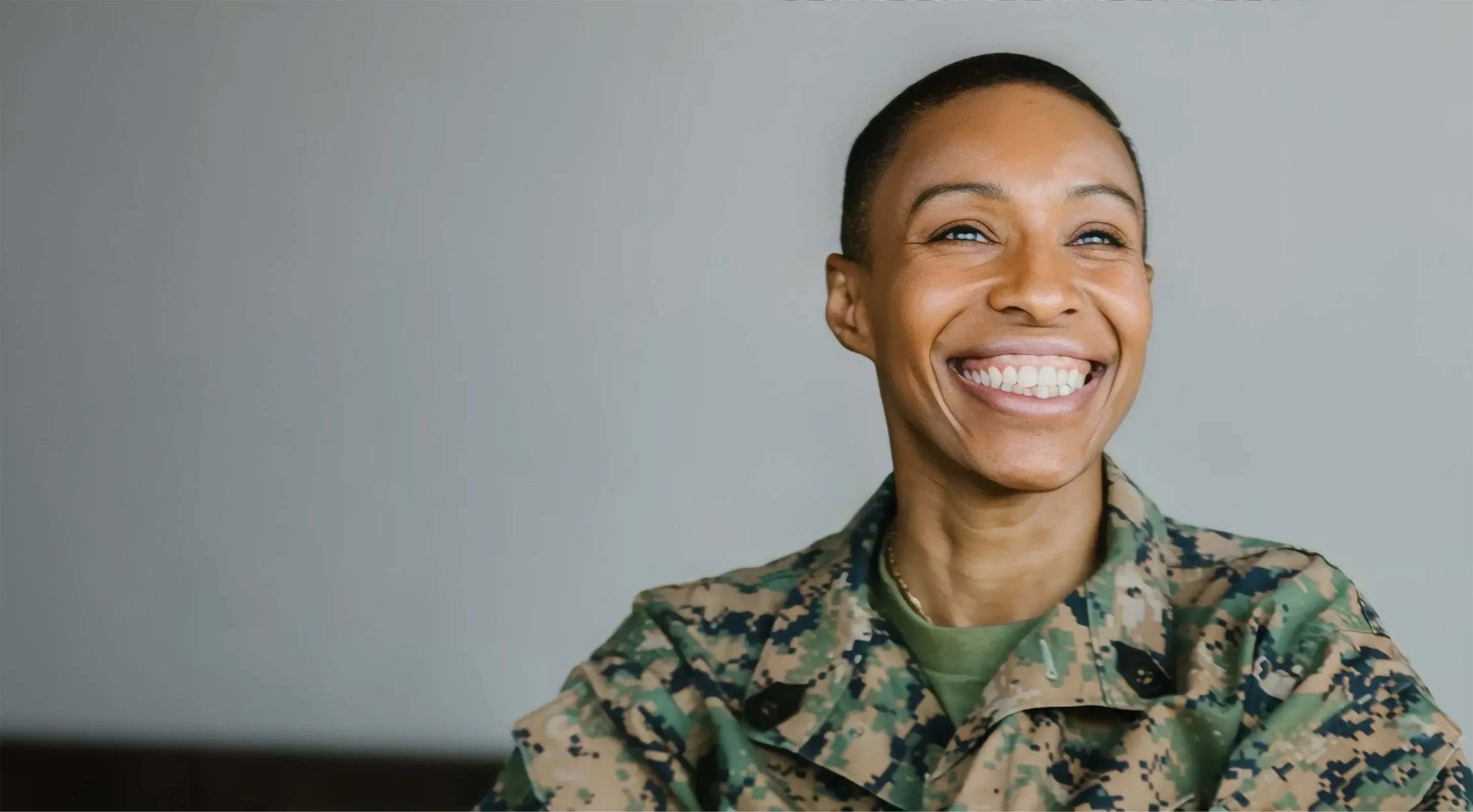 A female soldier wearing camouflage smiles