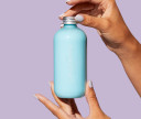 Hands holding an ocean blue customized conditioner bottle