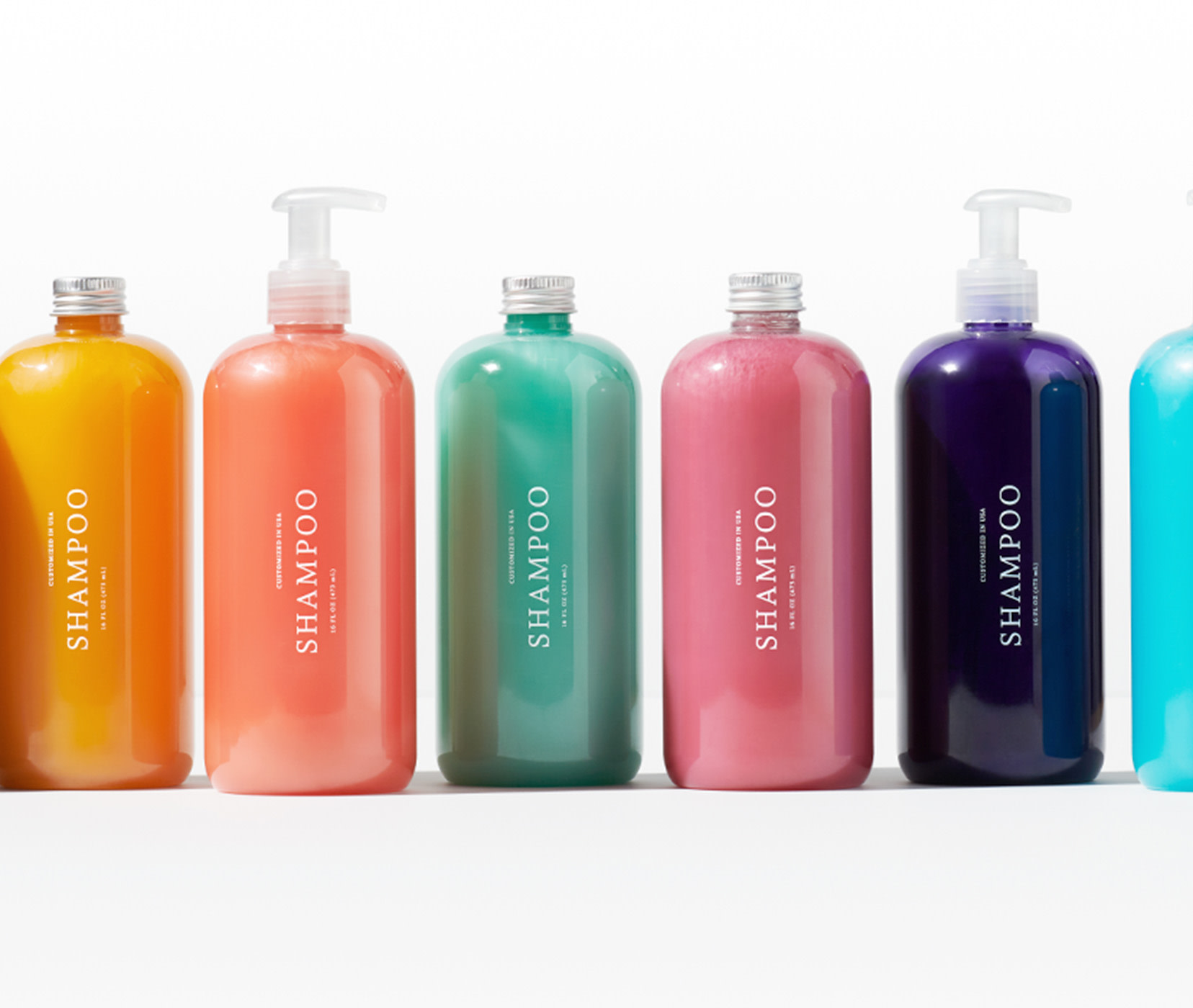 Customized shampoo bottles lined up next to each other. Shows bright colors of shampoo options in yellow, orange, green, pink, dark purple and ocean blue. 