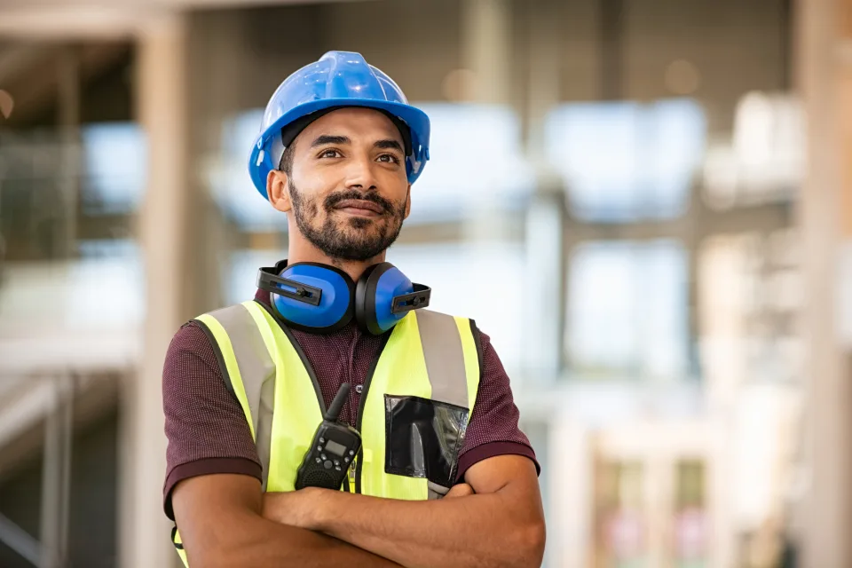 Bauarbeiter trägt einen blauen Helm und eine Warnweste