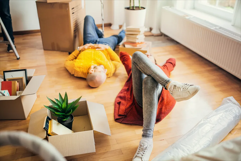 Mann und Frau liegen auf dem Boden in ihrem neuen Apartment - Umzug, Vorteile für Bewohner