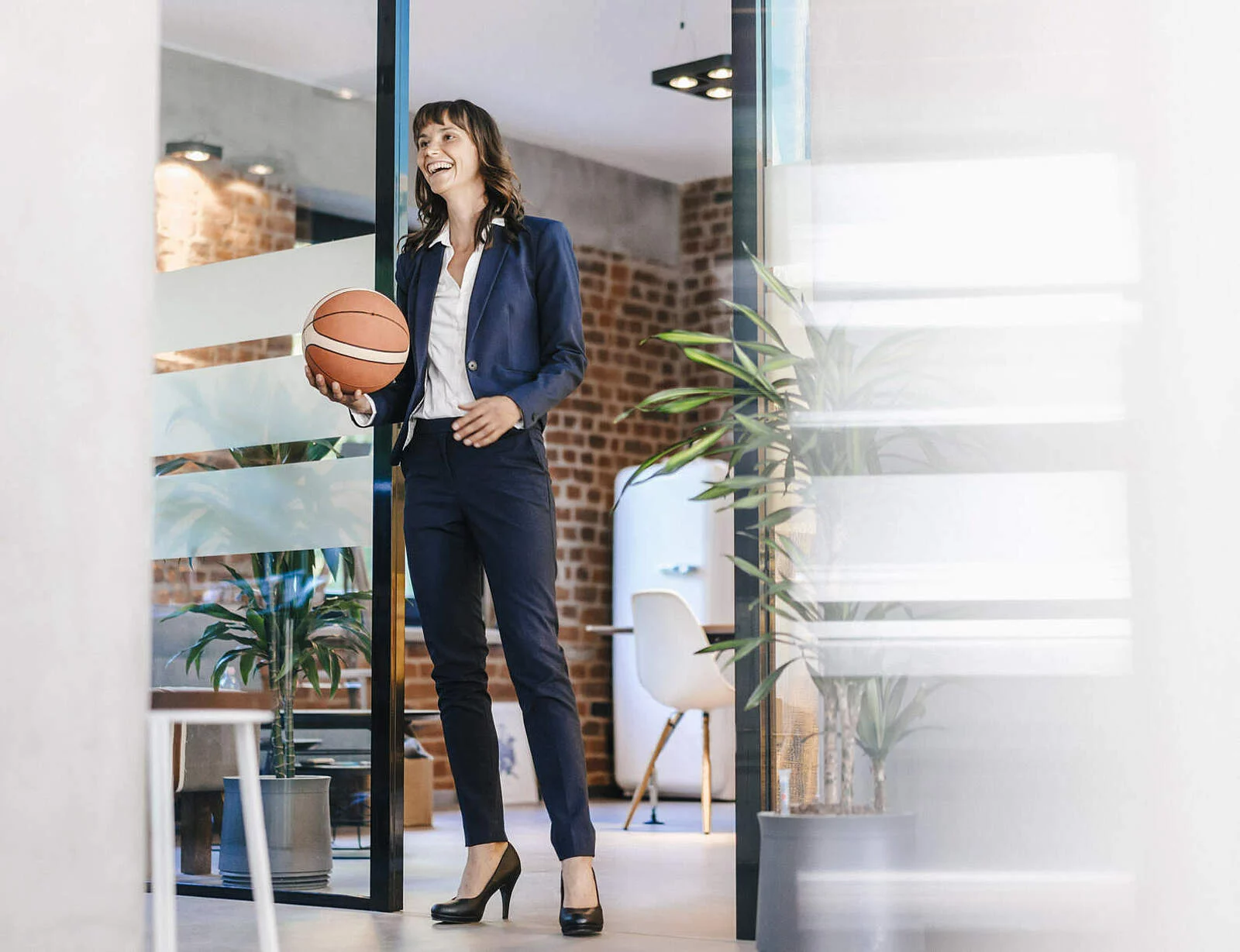Businessfrau hält einen Basketball in der Hand im Büro