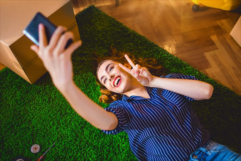 Frau liegt auf dem Boden und macht ein Selfie