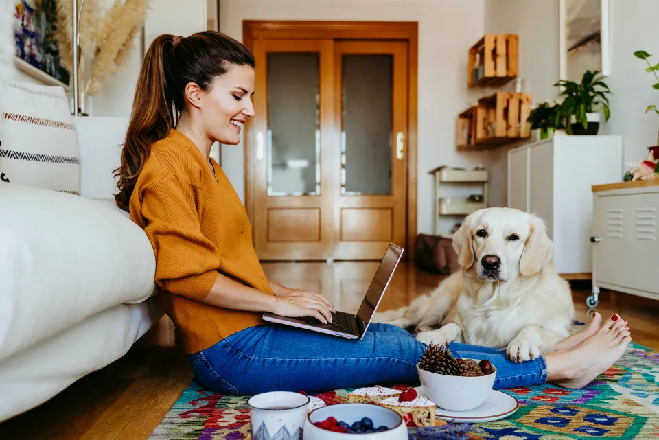 Wohnungswirtschaft Frau sitzt mit Hund vor der Couch auf dem Boden und surfen im Internet