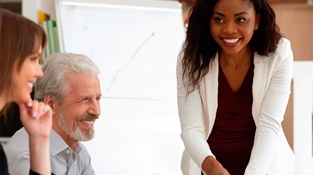 Happy woman standing while colleagues sit during meeting