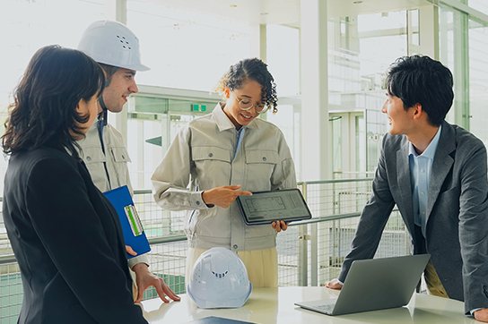 Diverse group of engineers in business professional clothes standing while looking at tablet