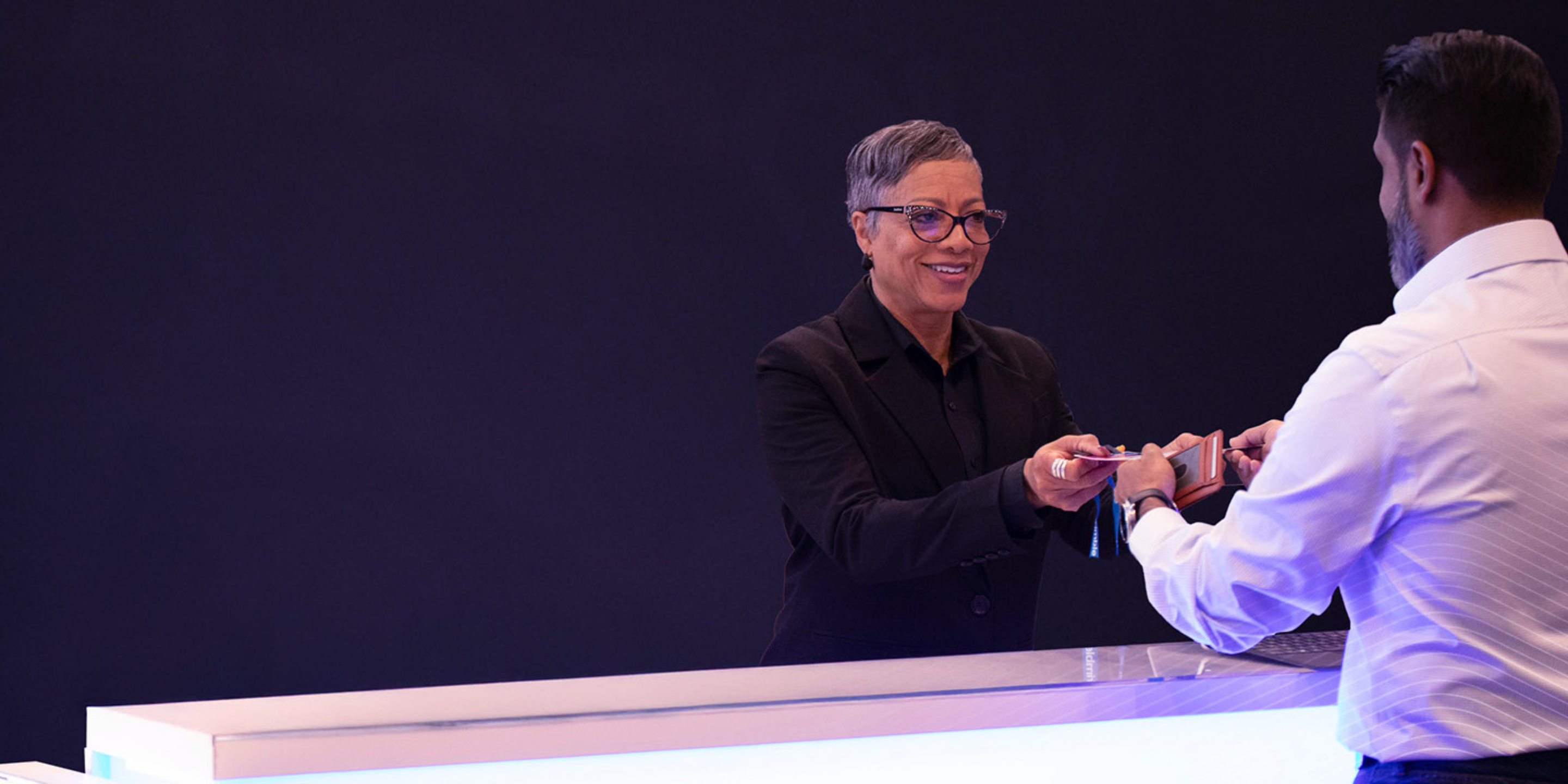 A Trimble employee hands a badge over to a Dimensions attendee checking in for the conference.