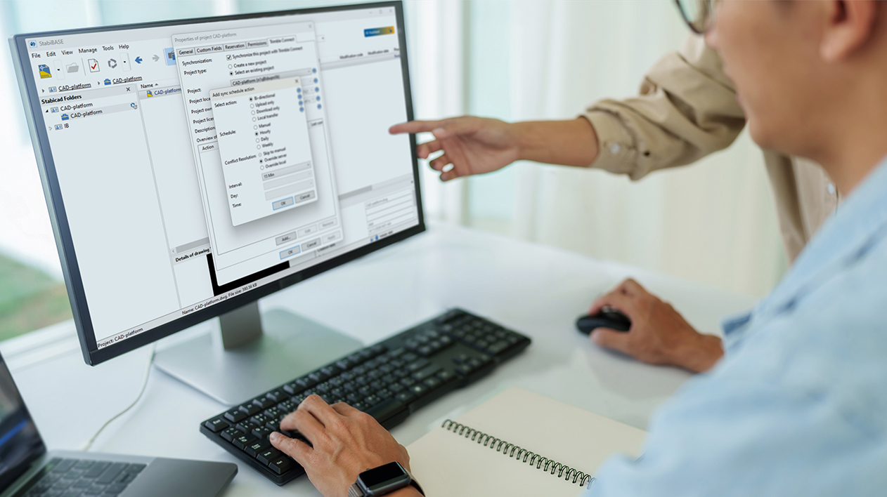 Two people collaborating at a computer screen showing the Stabicad for IntelliCAD software interface.
