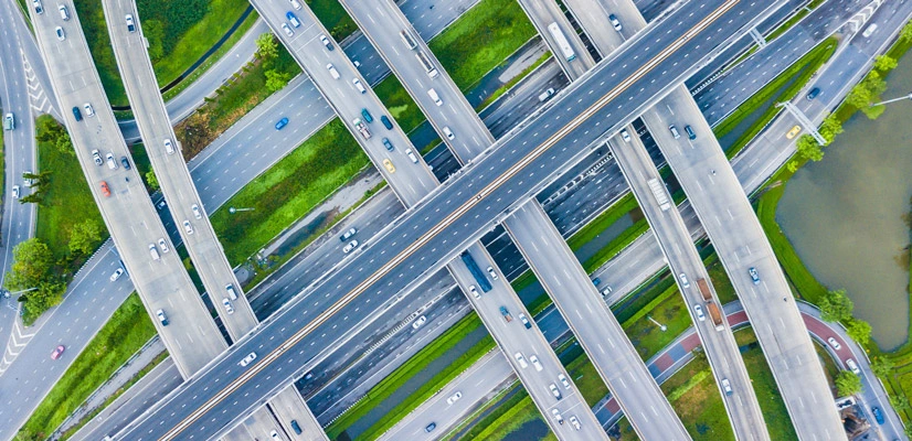 Aerial top-down view of a complex multi-level highway interchange with various traffic lanes and green landscaping.