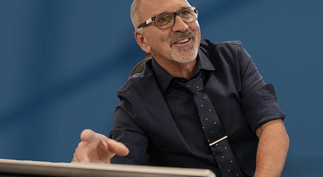 A middle-aged man with glasses and a goatee, identified as Trimble President and CEO Rob Painter, gestures while speaking in a professional setting.