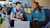 Two young professionals talking in casual setting while using laptop