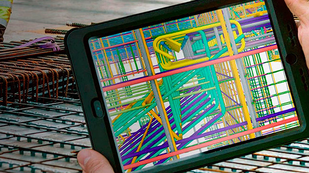 A person holds a ruggedized tablet displaying a detailed 3D architectural or engineering model, featuring a complex network of colorful pipes and structural elements.