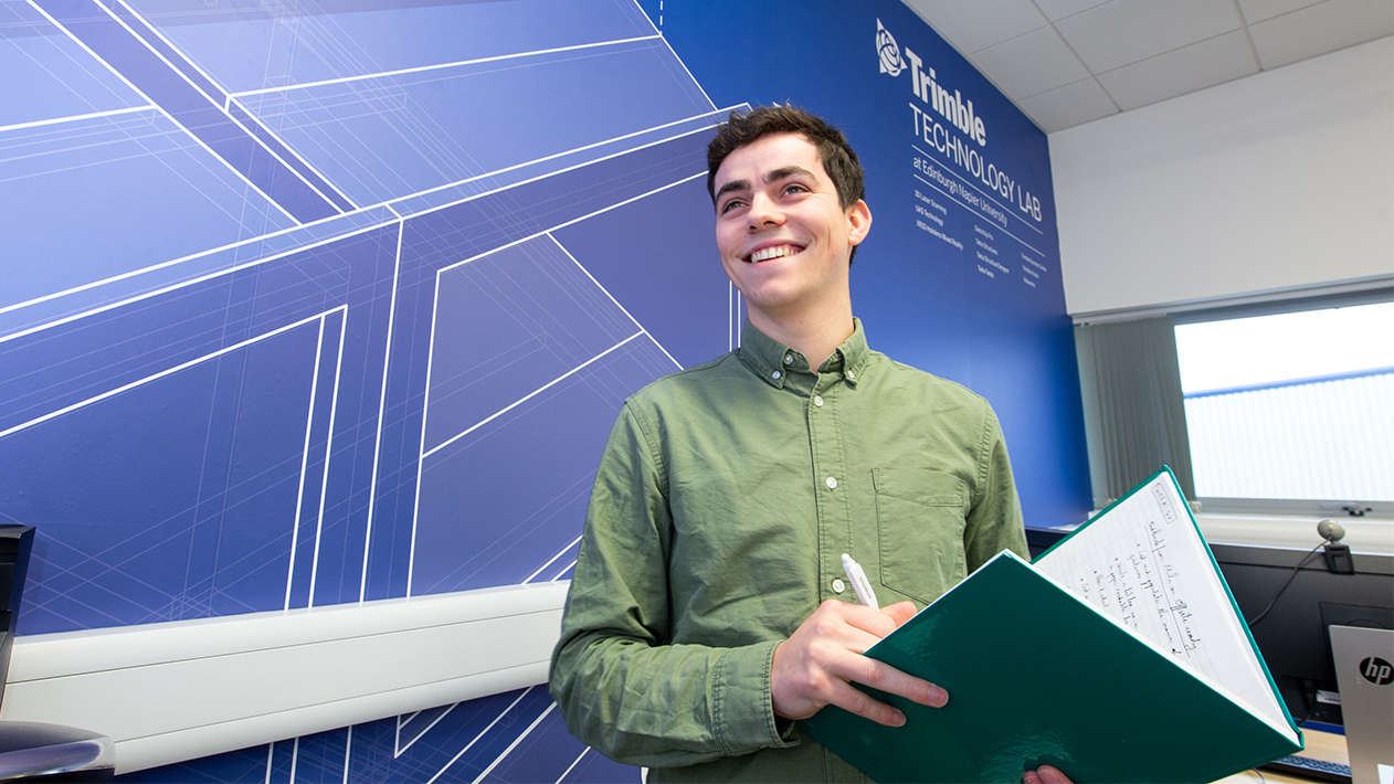 Student at Edinburgh Napier University TTL smiling while holding notebook