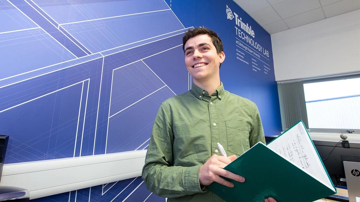 Student at Edinburgh Napier University TTL smiling while holding notebook