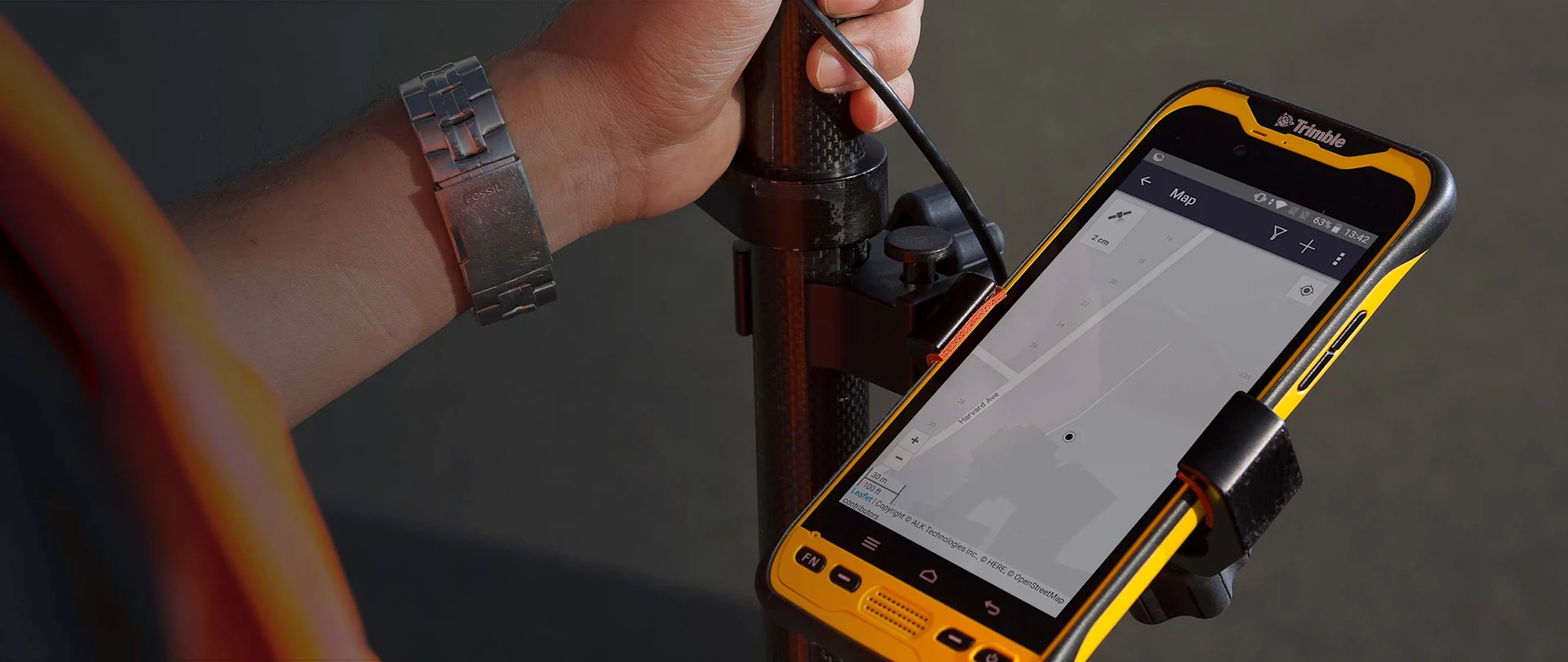 Close-up of yellow mobile device showing Trimble GPS technology.
