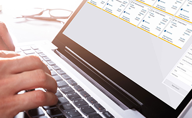 A person uses a laptop displaying the Trimble ProjectSight dashboard, featuring a grid of project cards with yellow accents and assignment details.