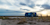 A blue Trimble Airstream trailer at sunset. Two professionals use a surveying scanner on a tripod and a drone in an open landscape.
