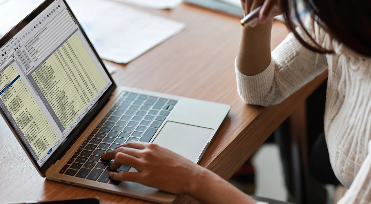 A woman uses Trimble Accubid Classic estimating software on a laptop to prepare a commercial construction estimate.