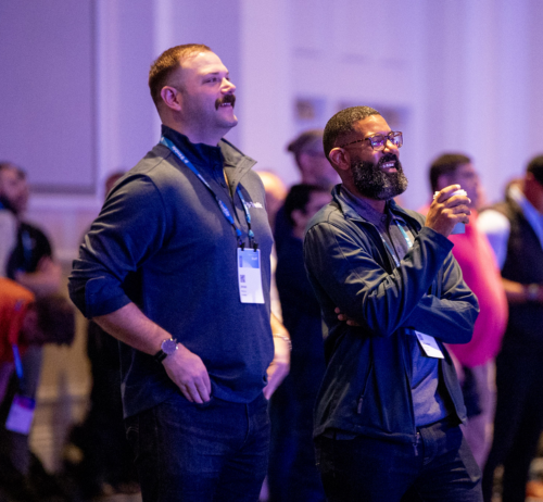 Two Dimensions attendees are smiling and laughing while watching the Dimensions keynote.