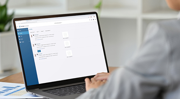 A woman uses Trimble Connect on a laptop to manage project activity and construction data in an office environment.