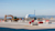 Construction barriers and heavy machinery at airport runway with airplane in background