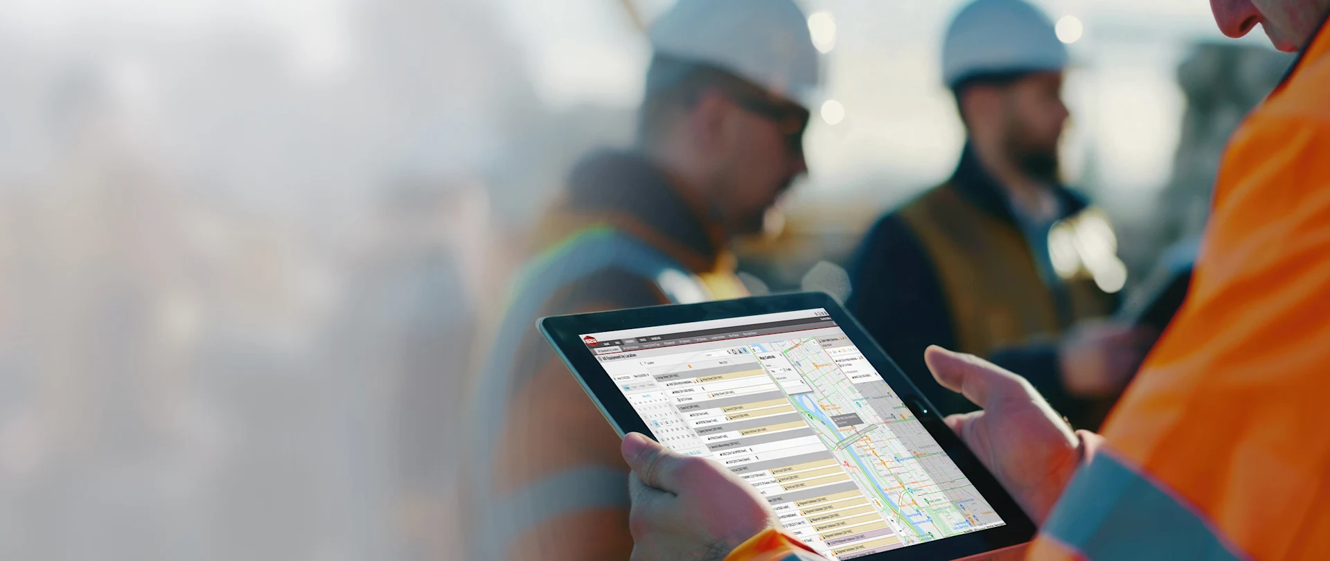 A construction worker uses a tablet displaying Trimble’s B2W software to monitor equipment locations at a job site.
