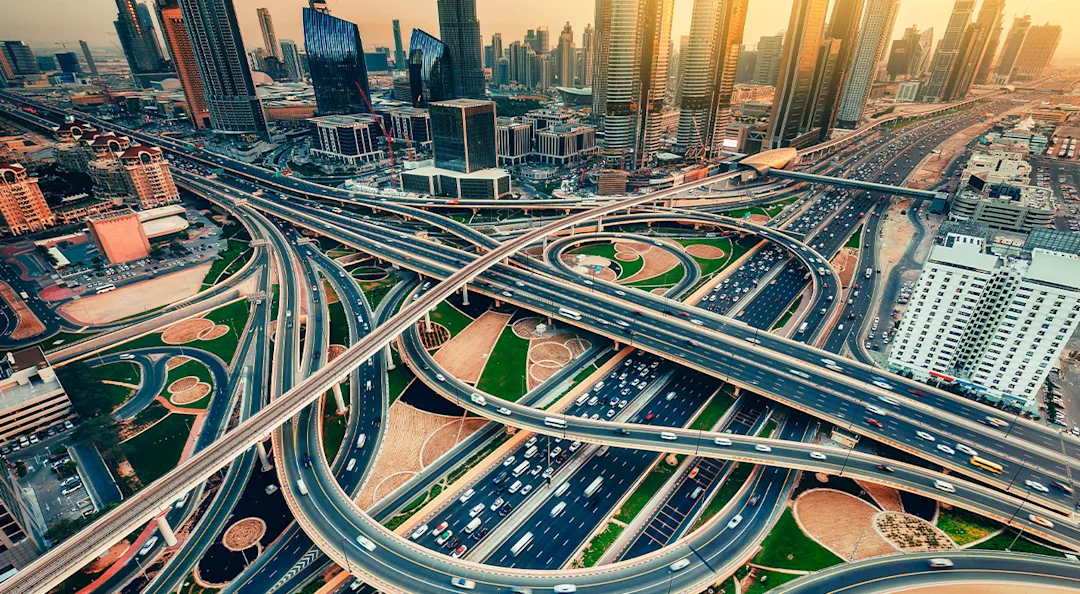 Luftaufnahme eines mehrstöckigen Autobahnknotenpunkts, umgeben von Wolkenkratzern.