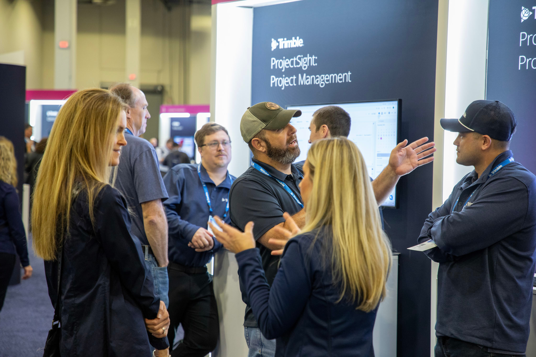 Attendees network with each other while standing in front of the ProjectSight: Project Management kiosk in the Expo Hall.