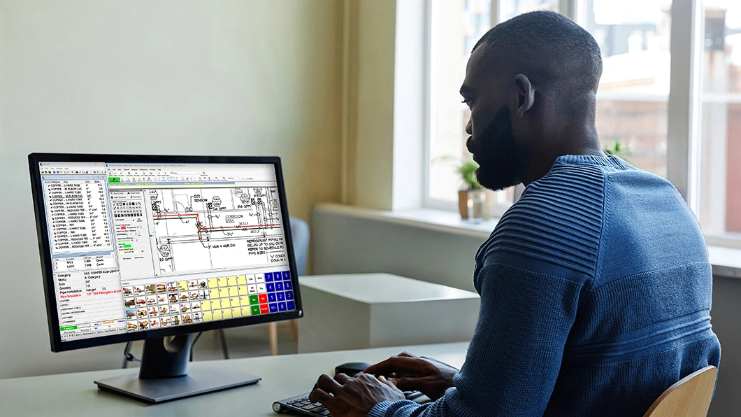 A person works at a computer, using Trimble Estimation Desktop digital takeoff and estimating software on the screen.
