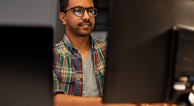 A man wearing glasses and a plaid shirt works at a computer monitor in a professional setting, featured on a Trimble product page.