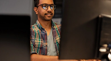 A man wearing glasses and a plaid shirt works at a computer monitor in a professional setting, featured on a Trimble product page.